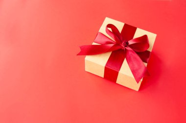 Kırmızı arkaplanda kırmızı saten kurdeleli kırmızı renkli kare bej kutu ve metin için boşluk. Şenlik hazırlanmış düzen biçimi minimalizm tek renkli