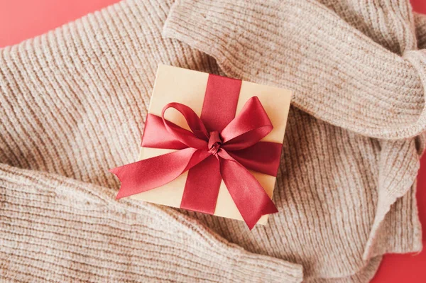 居心地の良い休日カード ベージュのニットセーターに赤いお祝いサテンリボンとベージュボックス 選択的焦点 — ストック写真