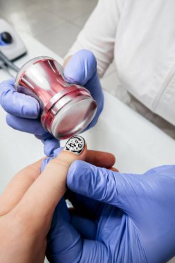 Salondaki manikür seçici odak süreci eldivenli eller beyaz tırnakları pullu dekore eder. Uyum sağlanırken ölçülere, dikey içeriğe