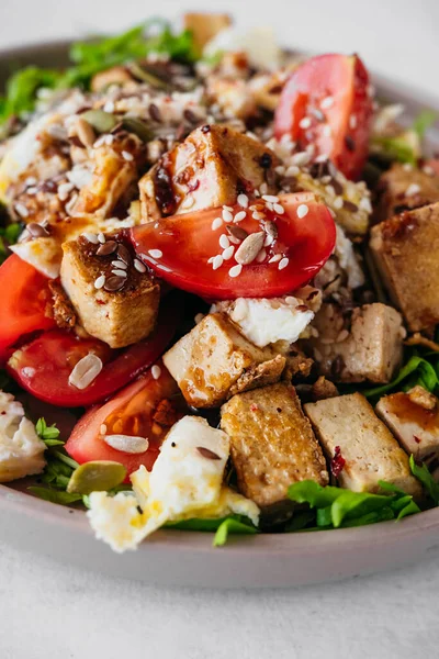 Tofu peyniri, domates, yumurta, sos, susam tohumu ve tohumdan oluşan sağlıklı bir diyet salatası tarifi. dikey vejetaryen gıda içeriği, yakın plan, seçici odaklanma