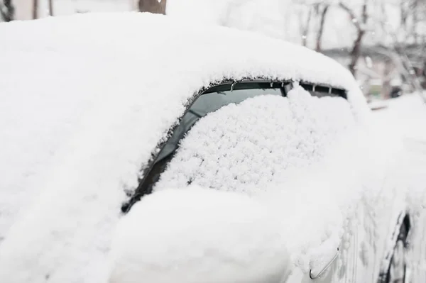 car completely covered with snow, blocked and does not open. Dangerous road conditions. Cleaning cars from ice, selective focus