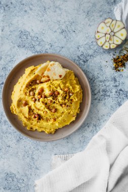 beautiful serving of chickpea hummus with olive oil, garlic, spices and roasted grains on kitchen table with cotton napkin, vertical food content, simple recipes cooking at home, selective focus