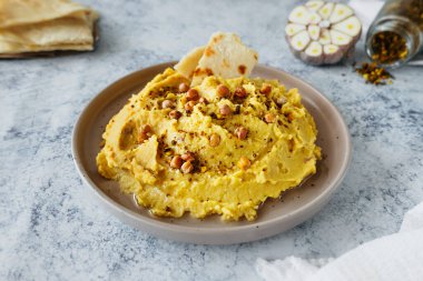 beautiful serving of chickpea hummus with olive oil, garlic, spices and roasted grains on kitchen table with cotton napkin, food blog, simple recipes cooking at home, selective focus