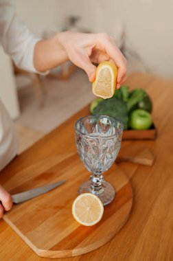 Limon suyunu hazırlamak için adım adım talimatlar. Yüzü olmayan 5. adım limon suyunu hafif mutfakta cama sıkıyor. dikey sağlıklılık içeriği, seçici odak