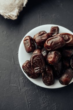 Ramazan ayında geleneksel iftar akşam yemeği. Koyu arkaplan görünümlü farvor plakalı kurutulmuş tarihler. Geleneksel oryantal tatlılar. sağlıklı doğal çerez. dikey, seçici odak
