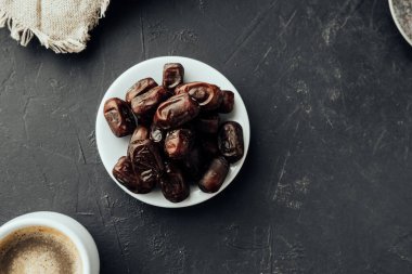 Farvor tabağında kurutulmuş tarihler ve arka planda koyu renk kahve fincanı. Geleneksel oryantal tatlılar. sağlıklı doğal çerez. seçici odak