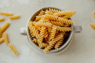 Spiral tortiglioni makarna mermer tabakta ve arka planda iki tutacağı var. Buğdaydan yapılmış ev yapımı makarna. Çiğ yemek. yiyecek içeriği, seçici odak