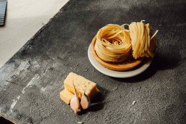 Ev yapımı Pappardelle çiğ makarna, hamurlu merdane, un ve karanlık mutfakta flüt bıçağı. El yapımı buğdaydan makarna yapma süreci. Yemek blogu. seçici odak