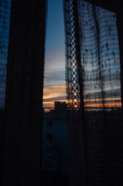 Gün batımında güneşten gelen sıcak turuncu ışık tülün içinden ve penceredeki perdeler. Alçakgönüllülük. Ruh hali tonu.