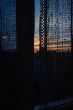 Gün batımında güneşten gelen sıcak turuncu ışık tülün içinden ve penceredeki perdeler. Alçakgönüllülük. Ruh hali tonu.