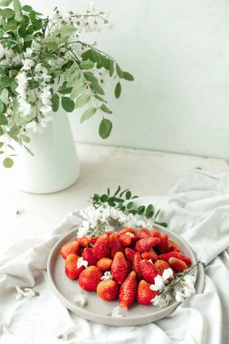 Tabakta taze çilek ve dekor olarak küçük beyaz çiçekler. Sağlıklı yemek. Çiğ gıda diyeti. mevsimlik böğürtlen seçici odak