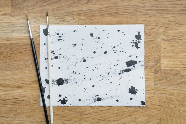 Manchas de tinta sobre un papel blanco sobre una superficie de madera — Foto de Stock