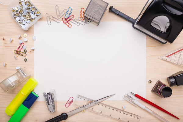 Office supplies and a white piece of paper in the center