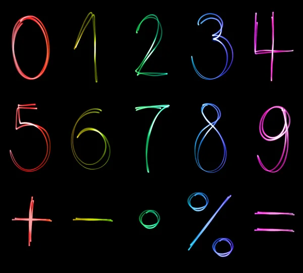 Различные флуоресцентные числа и математические символы в разных неоновых цветах — стоковое фото