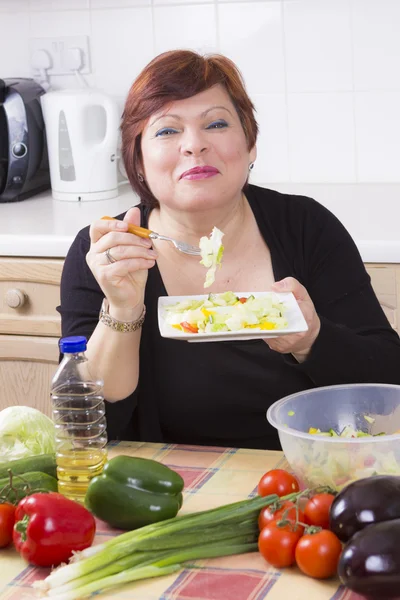Счастливая домохозяйка пробует овощной салат — стоковое фото