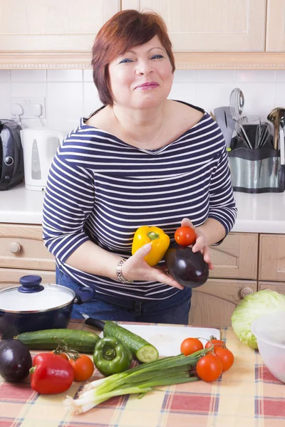 Hausfrau mittleren Alters kocht Gemüse lizenzfreie Stockbilder