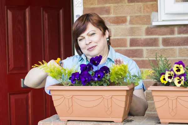 Donna felice prendersi cura di fiori all'aperto — Foto Stock