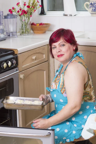 Mulher madura assar muffins em casa — Fotografia de Stock