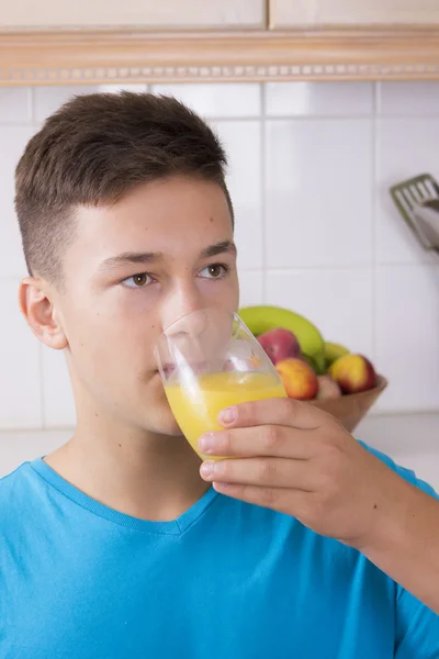 Menino com copo de suco na cozinha — Fotografia de Stock