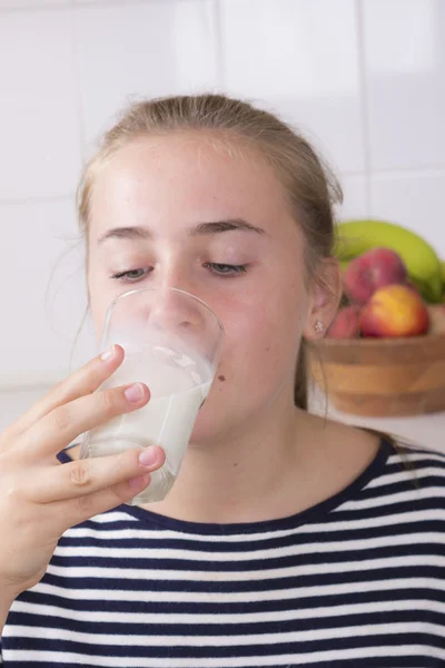 Menina com copo de leite na cozinha — Fotografia de Stock