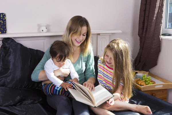 Madre leyendo a los niños en la cama Fotos de stock libres de derechos