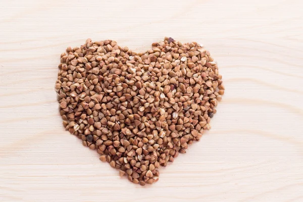 Heart-shaped buckwheat on wooden background — Stock Photo, Image