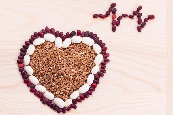 Hart-vormige boekweit met bonen op houten achtergrond — Stockfoto