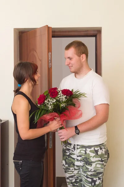 Lány találkozik barátja az ajtó melletti virágokkal — Stock Fotó