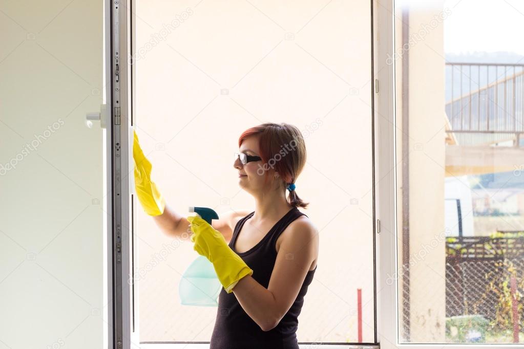 Pretty teenage girl washing window