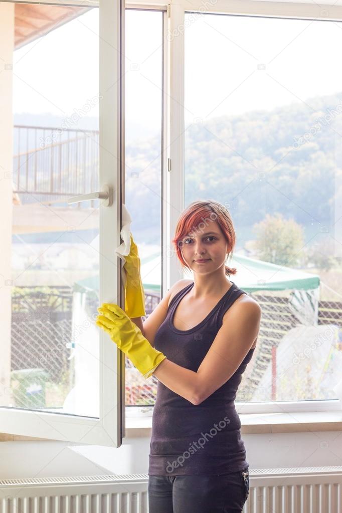 Pretty teenage girl washing window