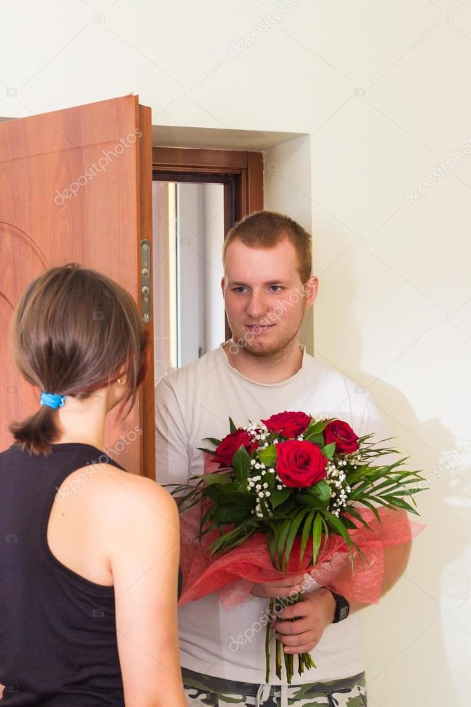 Girl meets boyfriend with flowers near the door