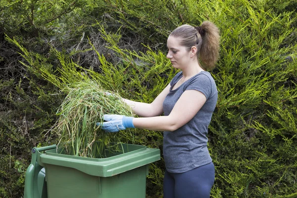 Ragazza con erba vicino bidone verde — Foto Stock