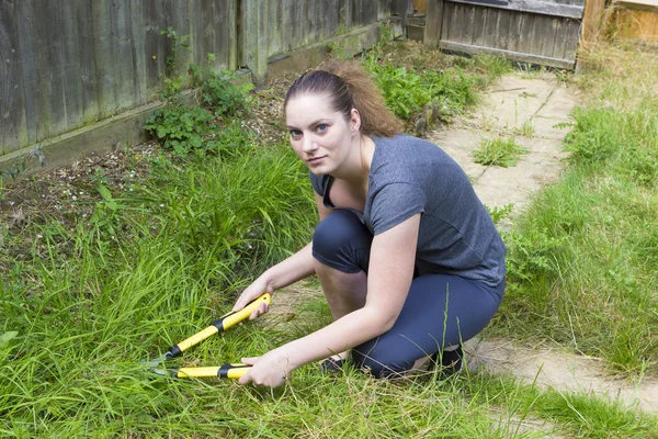 Mujer joven que trabaja con podadora de jardín en el jardín — Foto de Stock