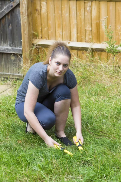 Giovane donna che lavora con potatrice da giardino in giardino — Foto Stock