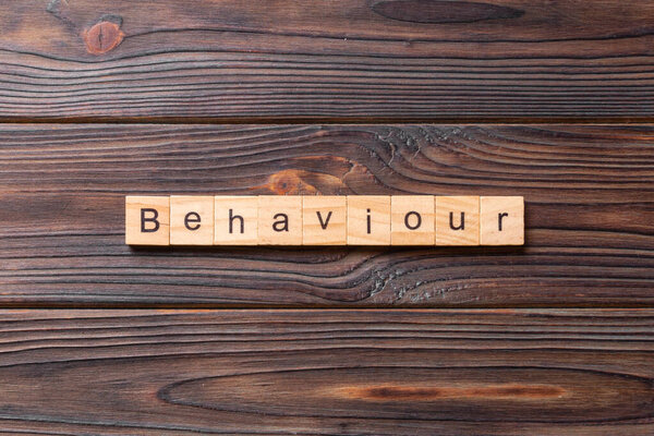 BEHAVIOUR word written on wood block. BEHAVIOUR text on cement table for your desing, concept.