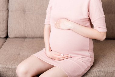 Hamile kadın, alt karın masajı yaptırıyor. İçeride, koltukta oturuyor. Hamilelik Sorunları Konsepti. Annelik sağlık hizmetleri.