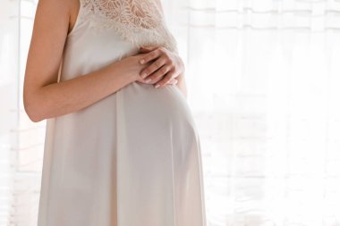 Evdeki pencerenin yanında duran güzel hamile kadın..