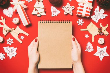 Kadın elinin rengarenk arka planda notlar aldığına dair üst görünüm. Yeni yıl süslemeleri ve oyuncakları. Noel zamanı konsepti.