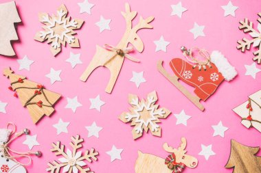 Şenlikli oyuncaklar, Noel sembolleri ve yeni yıl ağaçlarıyla süslenmiş pembe arka plan manzarası. Tatil kavramı.