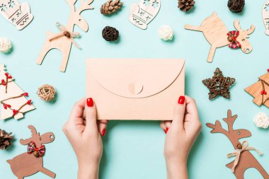 Bayram süslemelerinden yapılmış mavi arka planda bir zarf tutan kadının üst görüntüsü. Noel zamanı konsepti.