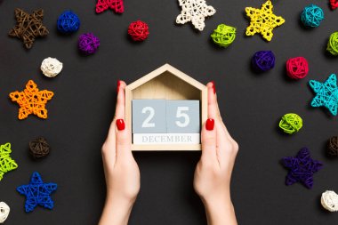 Siyah arka planda kadın eli takviminin üst görüntüsü. 25 Aralık 'ta. Tatil süslemeleri. Noel zamanı konsepti.