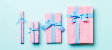 Noel 'i ya da diğer tatil hediyelerini mavi arka planda mavi kurdeleli kağıda sardım. Hediye kutusu, hediye dekorasyonu renkli masa, üst görünüm.