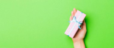 Kadın ellerinin Noel 'i ya da diğer tatil el yapımı hediye paketlerini avuçlarında tutuşu, fotokopi alanı olan düz masa arkaplanı..