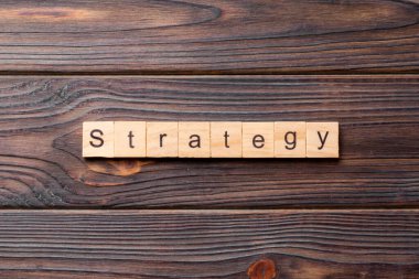 Tahta blokta STRATEGY kelimesi yazıyor. Beton masadaki STRATEGY metin desing, konsept için.