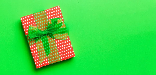 Top view Christmas present box with green bow on green background with copy space.