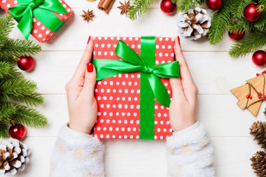 Elinde hediye kutusuyla neşeli tahta arka planda gezen bir kadının en iyi görüntüsü. Firavun ağacı ve Noel süslemeleri. Yeni yıl zaman kavramı.