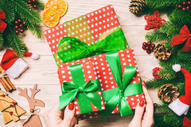 Elinde hediye kutusuyla neşeli tahta arka planda gezen bir kadının en iyi görüntüsü. Firavun ağacı ve Noel süslemeleri. Yeni yıl zaman kavramı.