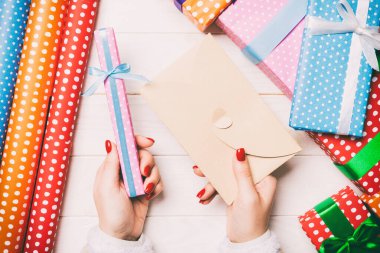 Bir elinde bir zarf, diğer elinde küçük bir hediye olan bir kadının ahşap arka planda üst görüntüsü. Yeni yıl süslemeleri. Noel zamanı konsepti.