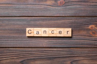 Kanserli kelime ahşap blokta yazılı. Deksing, konsept için CANCER metin çimento masa üzerinde.