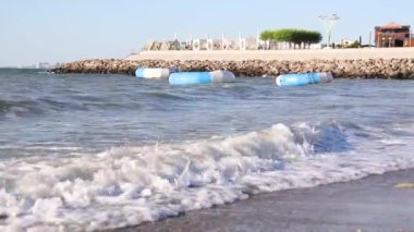 Deniz dalgaları kumlu bir plaja çarpıyor ve güneşli bir yaz günü beyaz su yaratıyor.